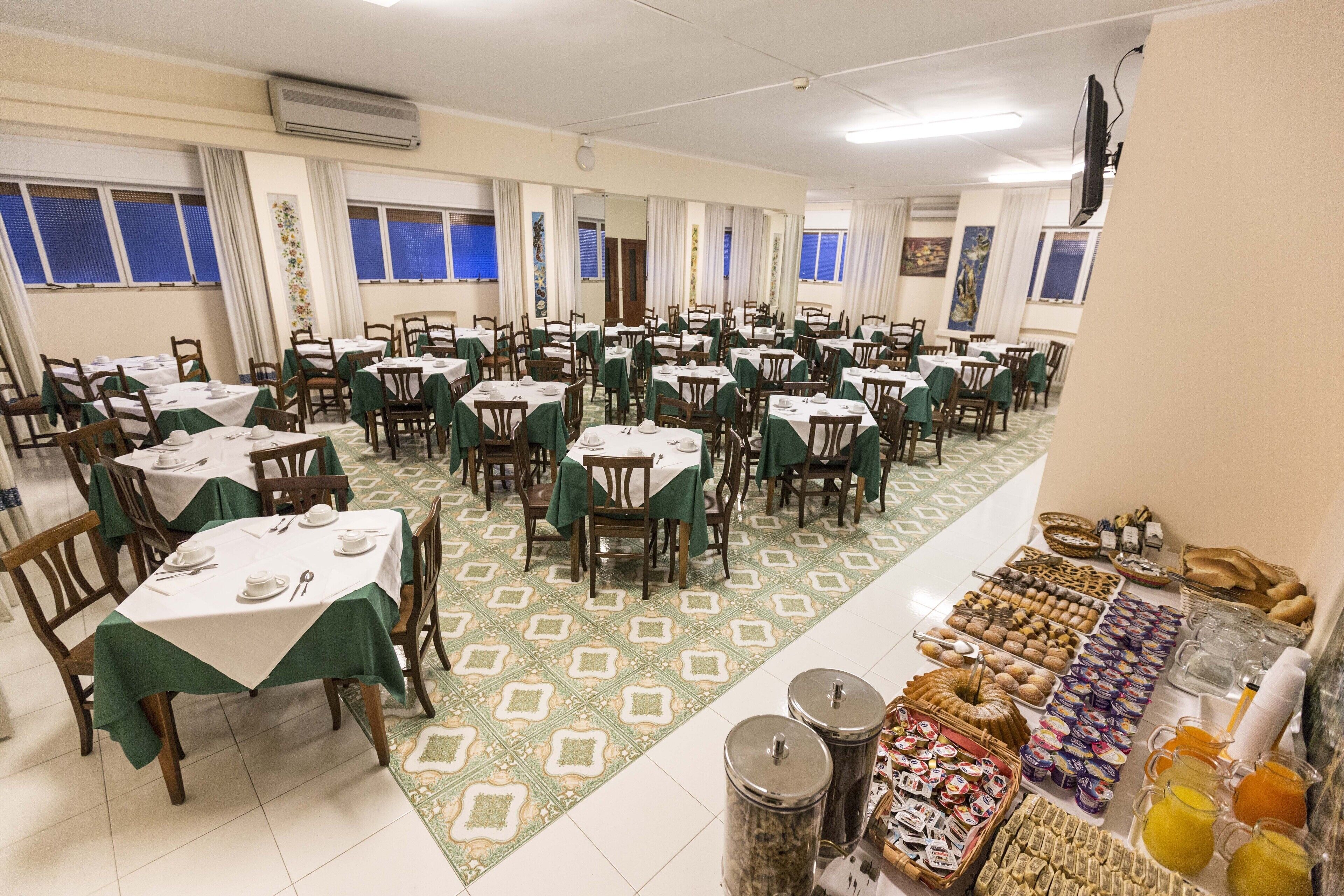 Ein Essbereich mit mehreren Tischen und Stühlen, ein Buffet mit verschiedenen Speisen und ein gemusterter Boden.
