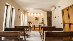 Een kerkinterieur met houten banken, een centraal altaar en een kruis.
