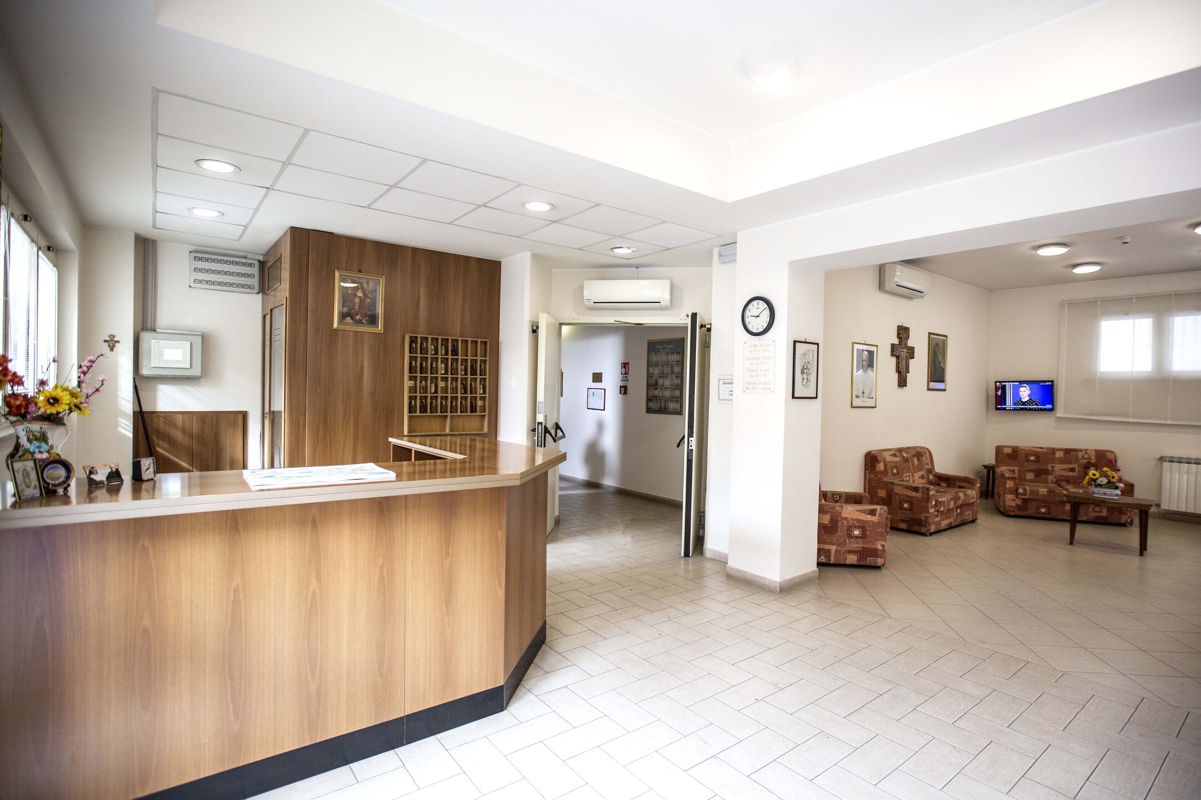 A reception area with a wooden counter, a clock, and a television.