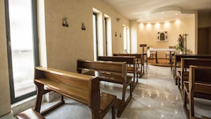 Een kerkinterieur met houten banken, een marmeren vloer en een standbeeld aan de muur.