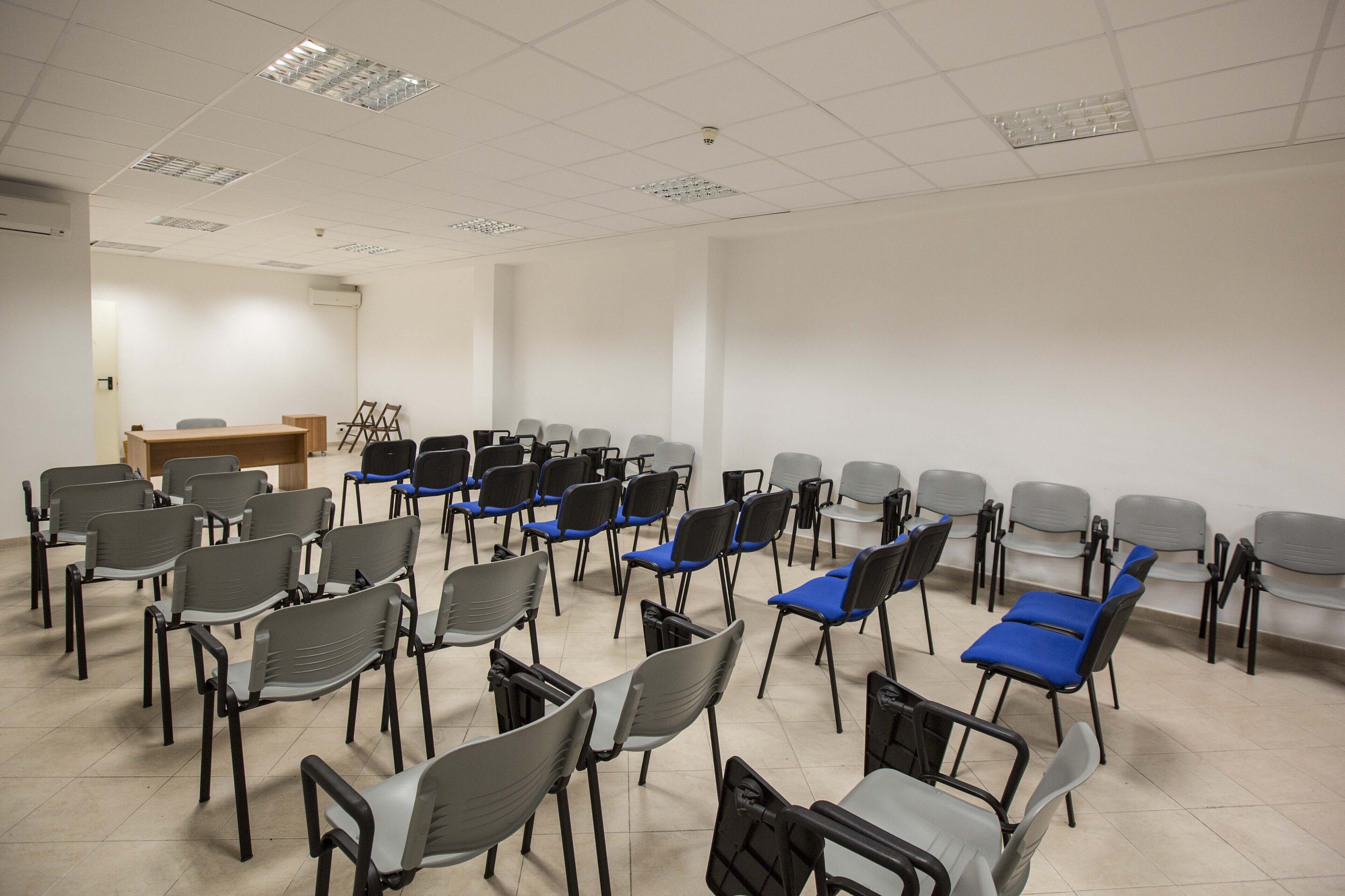 A conference room with rows of chairs, a podium, and a whiteboard.