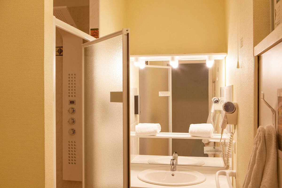 A bathroom with a sink, mirror, towel rack, and a hairdryer.