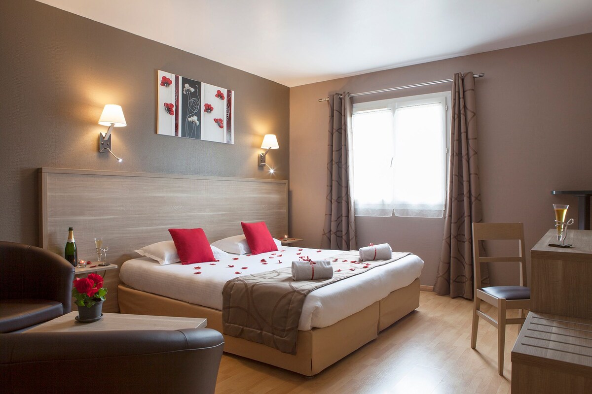 Een hotelkamer met een bed, nachtkastjes, een bureau, een stoel en een raam met gordijnen.