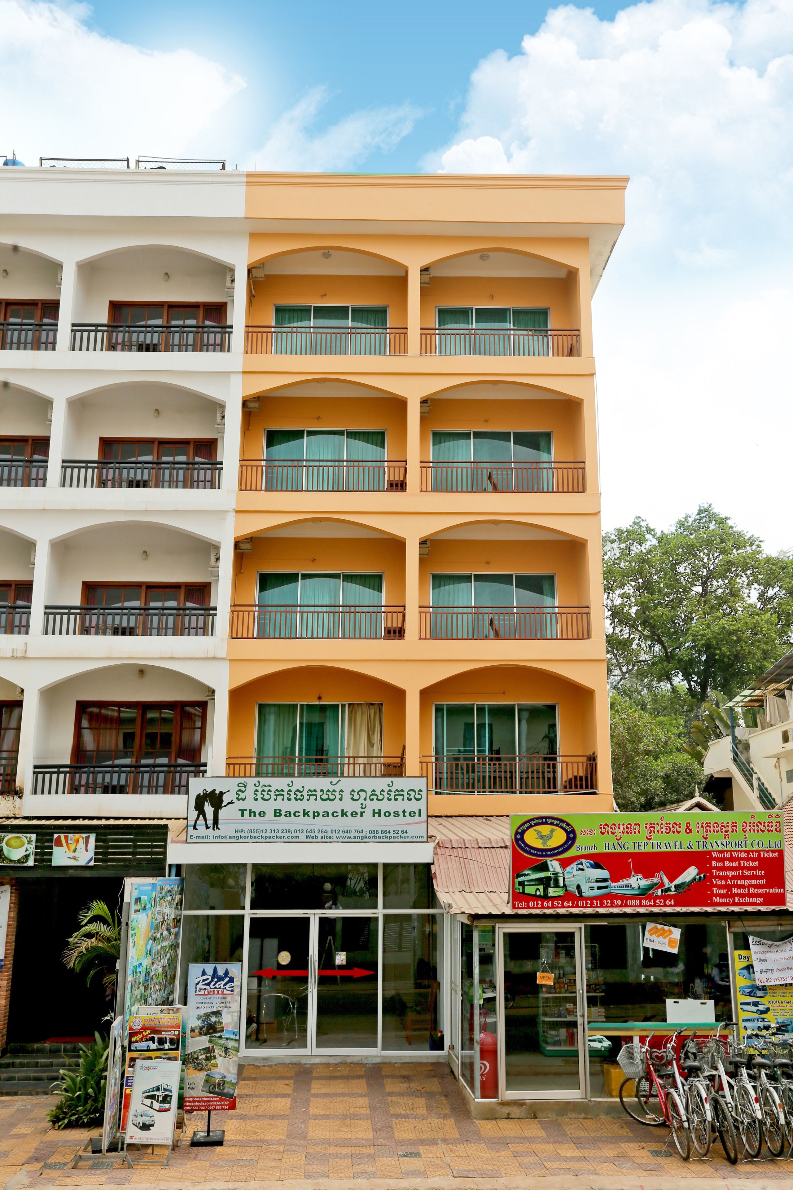 A multi-story building with balconies, a storefront with a sign, and bicycles parked outside.