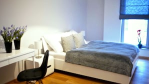 Ein modernes Schlafzimmer mit Bett, Nachttisch, Sessel und Schreibtisch.