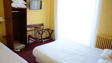 Una habitación de hotel con dos camas, un escritorio con silla, un televisor y un armario.