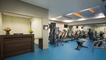 A gym with exercise equipment, a reception desk, and a mirror.