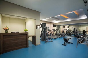 Un gimnasio con equipamiento de ejercicio, un mostrador de recepción y un espejo.