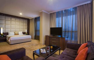 Ein Hotelzimmer mit einem großen Bett, einem Flachbildfernseher, einer Couch und einem Couchtisch.