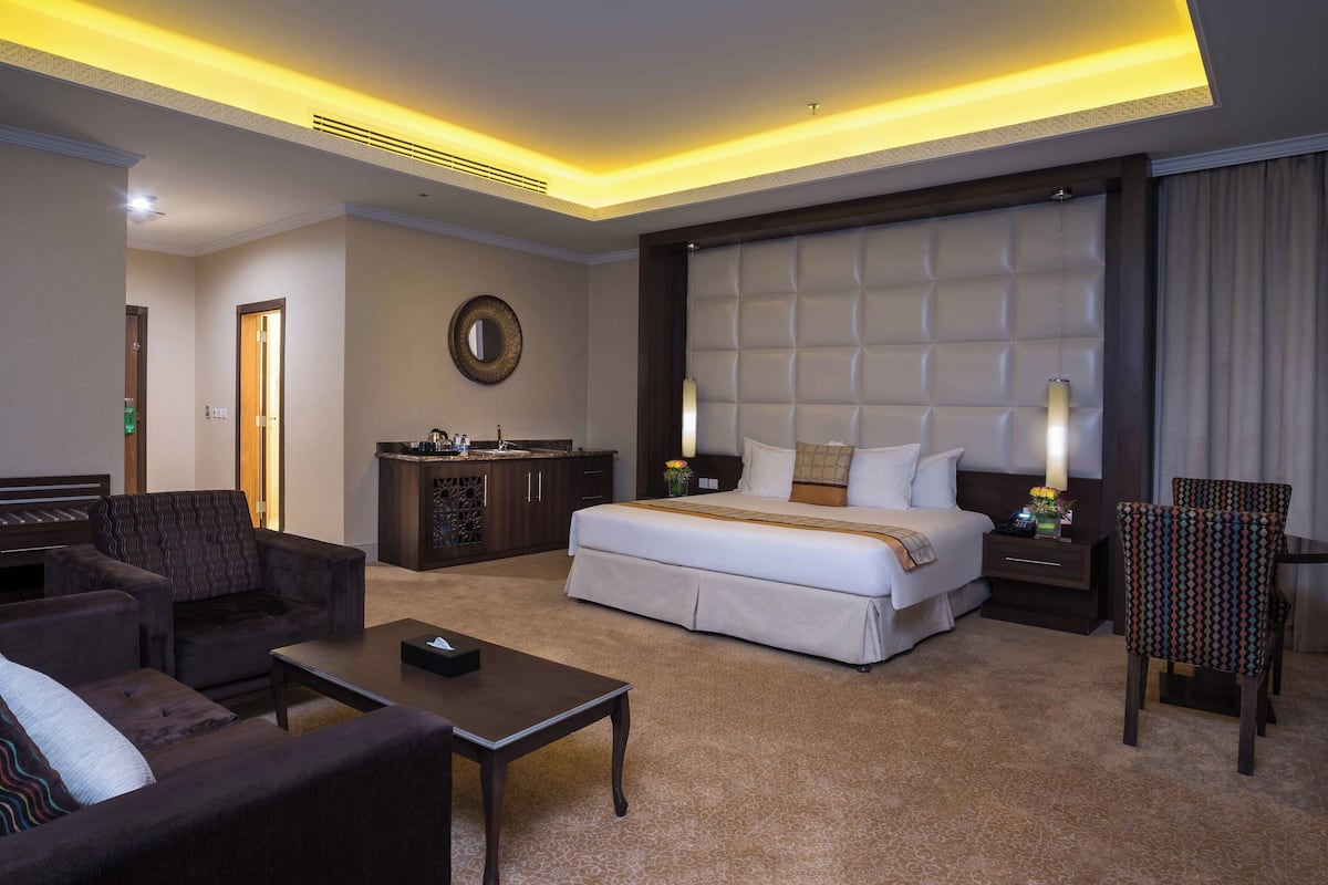 Habitación de hotel con una cama grande, un sofá, una mesa de centro, un escritorio y una silla.