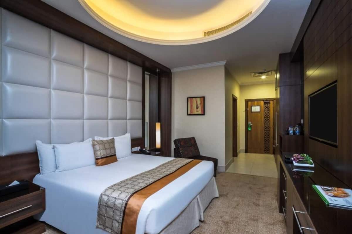 Una habitación de hotel con una cama grande, televisión, escritorio y minibar.