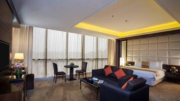Une chambre d’hôtel avec un grand lit, un canapé, une table basse et un téléviseur.