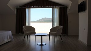 Una habitación con cama, dos sillas, una mesa y un ventanal con cortinas.