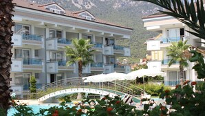 Un hotel de varios pisos con balcones, una piscina y un puente que conecta las construcciones.