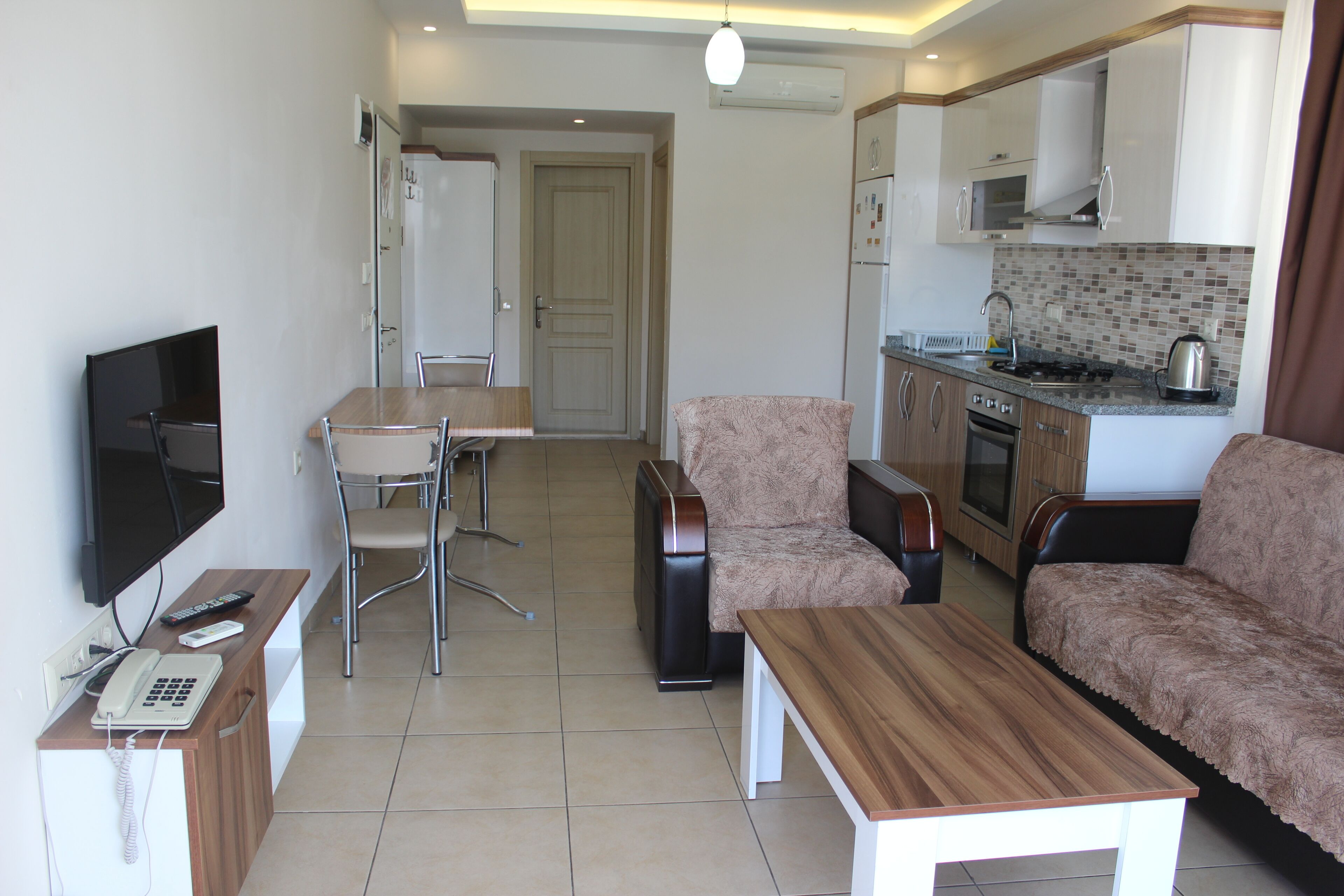 A modern living room with a sofa, a coffee table, a TV, and a dining area with chairs and a table.