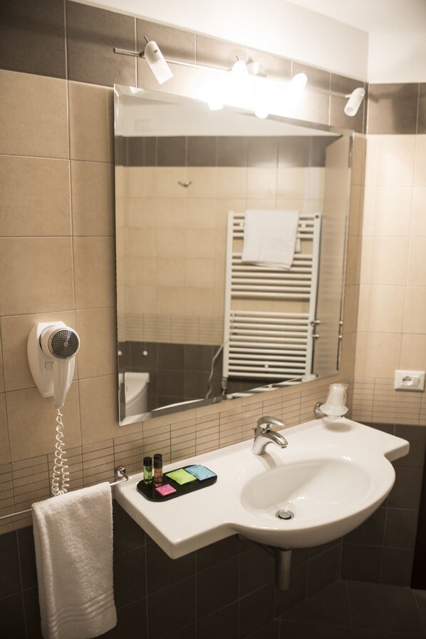 Une salle de bain équipée d’un lavabo, d’un miroir, d’un porte-serviettes et d’un sèche-cheveux.