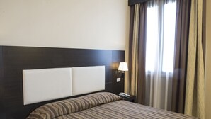A hotel room with a bed, a nightstand, a lamp, and a window with curtains. - Hotel Corte Business (Cavriago)