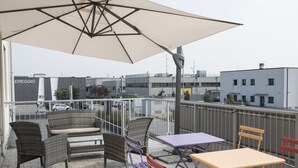 A rooftop terrace with wicker furniture, a table, and chairs. - Hotel Corte Business (Cavriago)