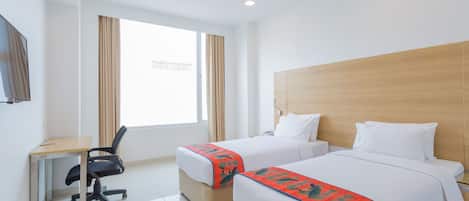 A hotel room with two beds, a desk, and a chair.