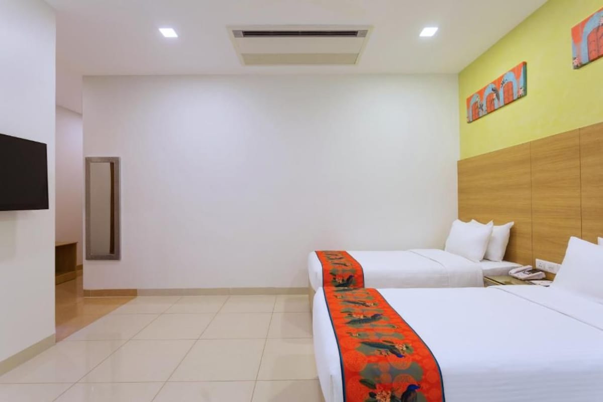 A hotel room with two beds, a flat-screen TV, a wooden headboard, and a door.