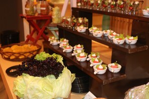 A buffet with various food items, including bowls of salad and a large pile of lettuce. - GINGER Noida City Center (Noida)