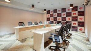 Une salle de conférence avec une longue table, des chaises, des bouteilles d’eau et un mur orné du logo de la marque « Ginger ».