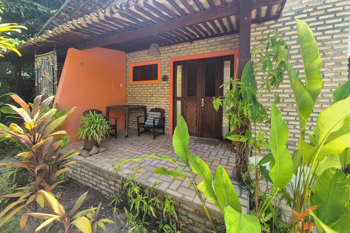 A covered outdoor area with a brick wall, a wooden door, and a small table with chairs.