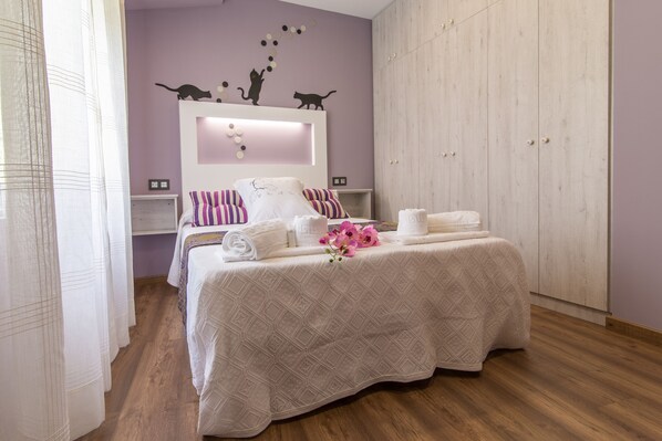 A bedroom with a bed, a wardrobe, a mirror, and a small shelf.