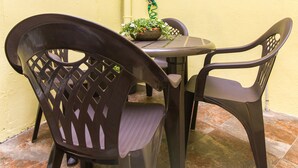 A small outdoor seating area with two chairs and a table, a potted plant, and a window. - Casa Carla (Palas de Rei)