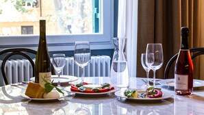 Een eettafel gedekt met borden eten, wijnglazen en wijnflessen.