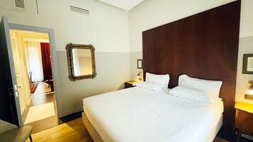 Une chambre d’hôtel avec un grand lit, une tête de lit en bois, une table de chevet avec une lampe et un miroir au mur.