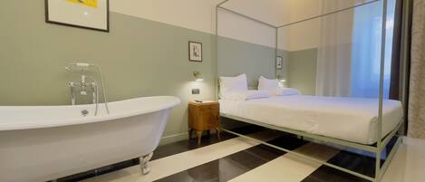Un baño moderno con una bañera independiente, una mesita de noche con lámpara y una cama con dosel.