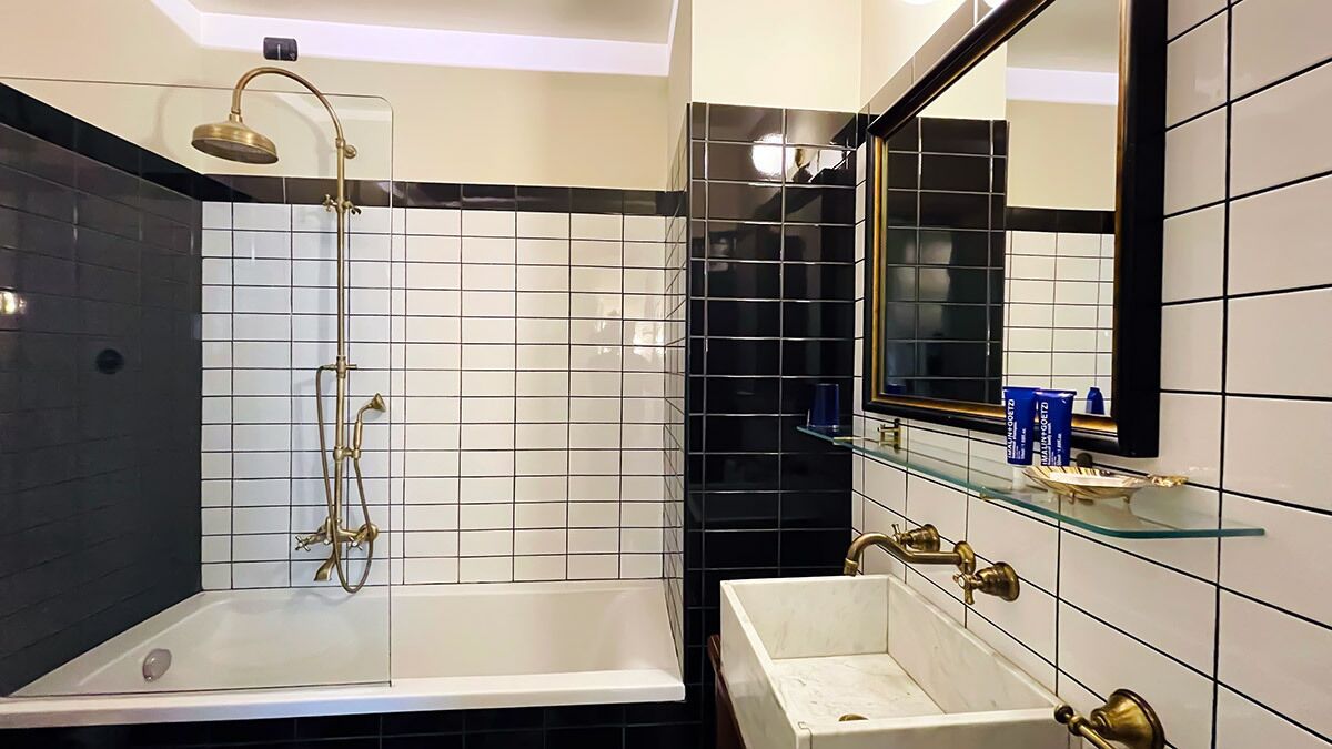 A modern bathroom with a glass-enclosed shower, a white bathtub, and a sink with a gold faucet.