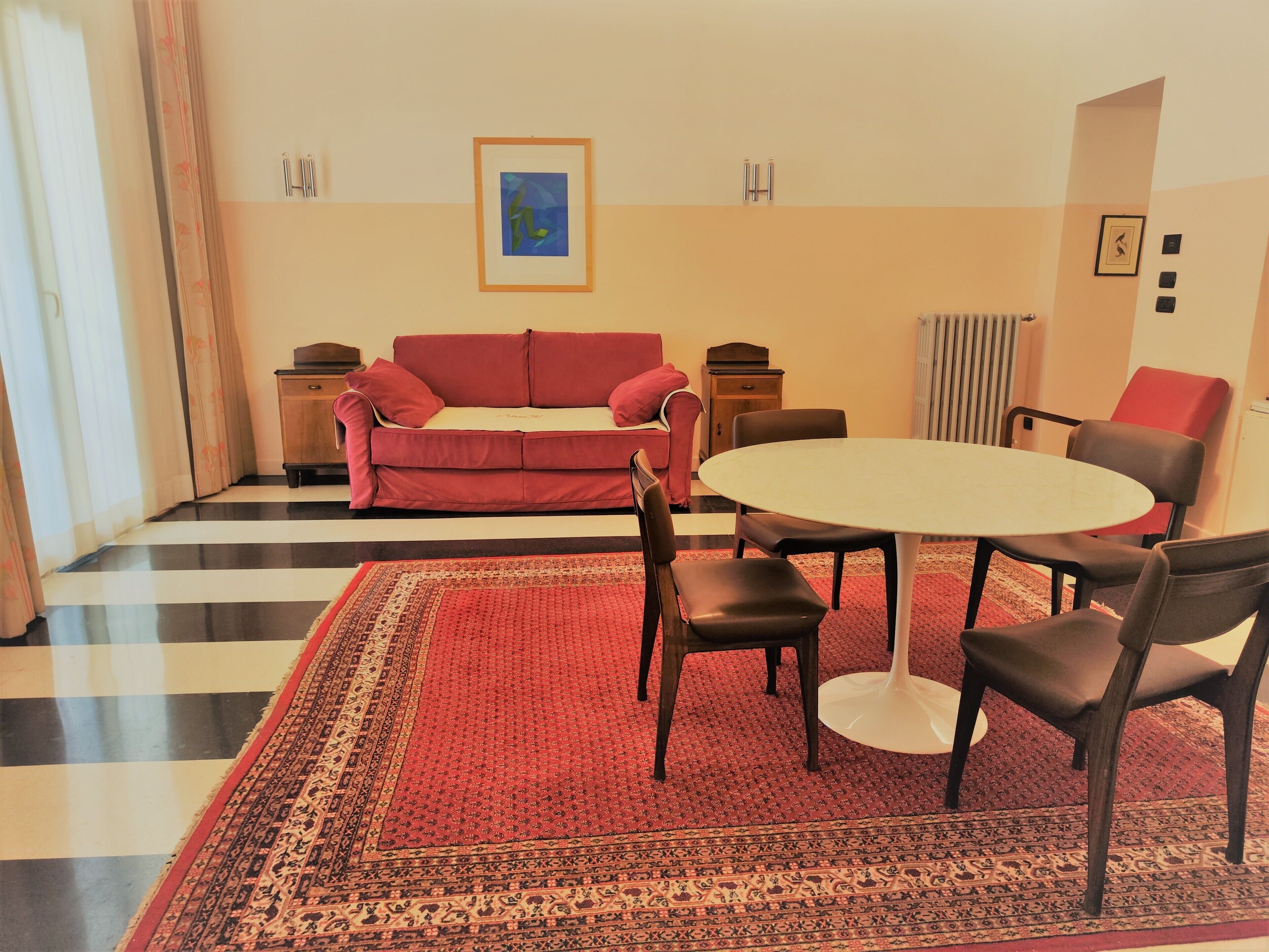 A living room with a red sofa, a round table, and a patterned rug.