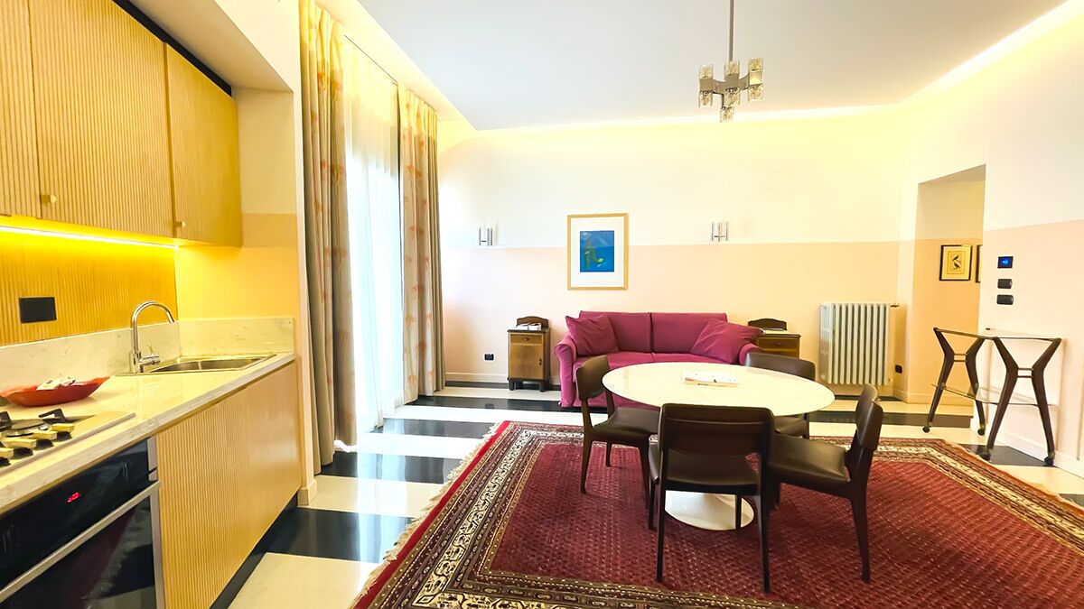 A modern hotel room with a kitchen, dining area, and a living space.