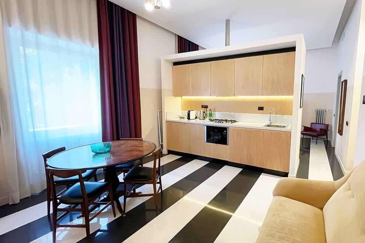 Una cocina moderna con horno empotrado, una mesa de comedor con sillas y un sofá en la sala de estar.