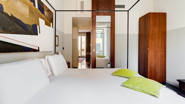 Een hotelkamer met een groot bed, een houten garderobe en een schilderij aan de muur.