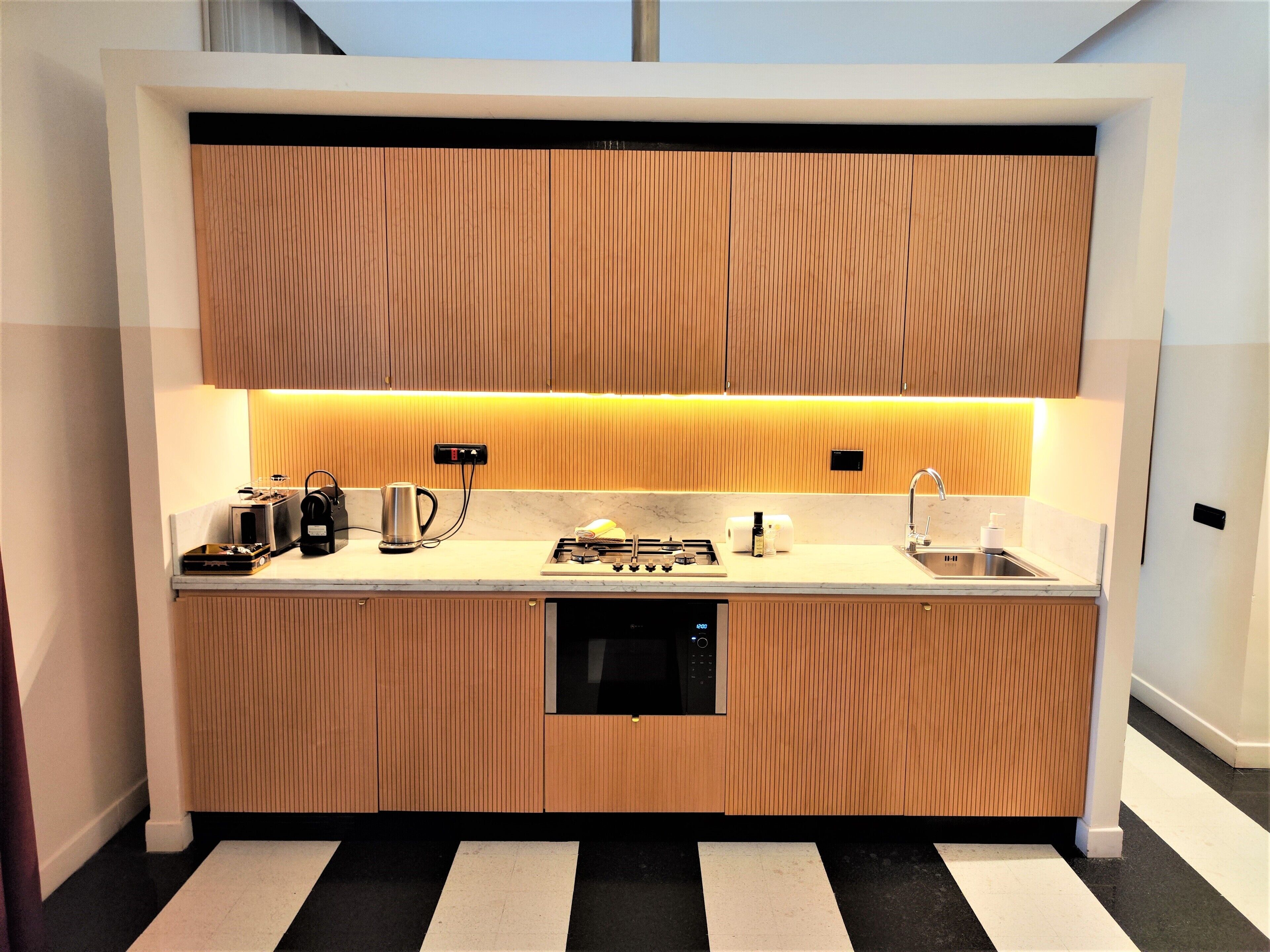 A modern kitchen with wooden cabinets, a built-in dishwasher, and a countertop with various appliances.