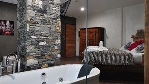 Un baño moderno con una pared de piedra decorativa, una bañera y un armario de madera.