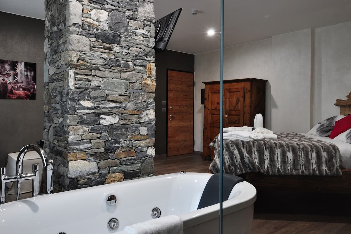 Une salle de bain moderne avec un mur d’accent en pierre, une baignoire et une armoire en bois.