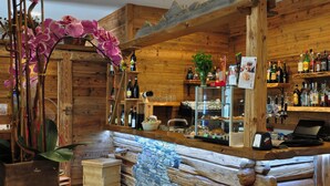 Un área de bar rústica con paredes de madera, una barra de piedra y diferentes botellas y vasos.