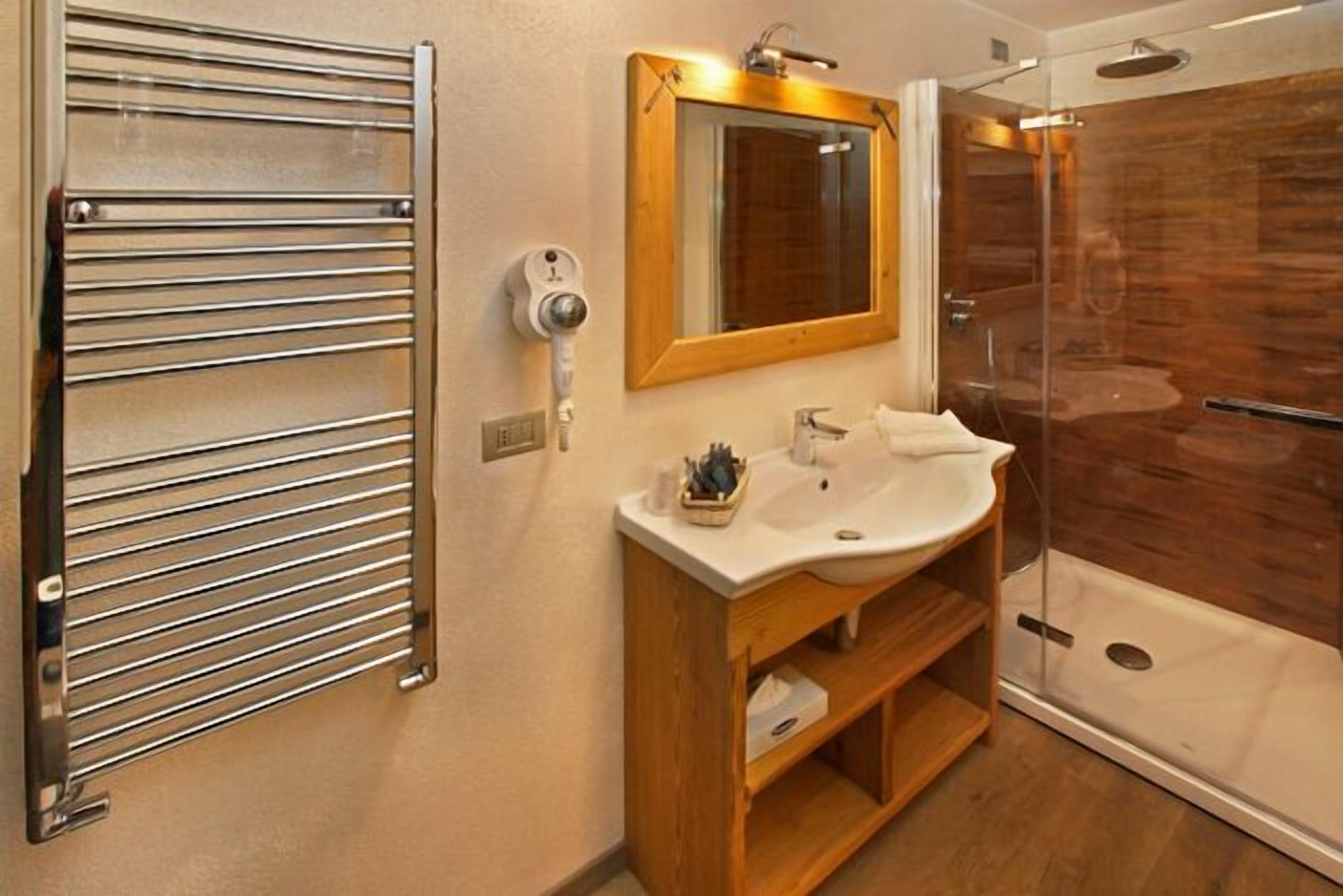 A modern bathroom with a glass shower enclosure, a wooden vanity, and a towel rack.