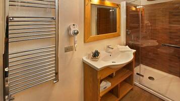 A modern bathroom with a glass shower enclosure, a wooden vanity, and a towel rack.