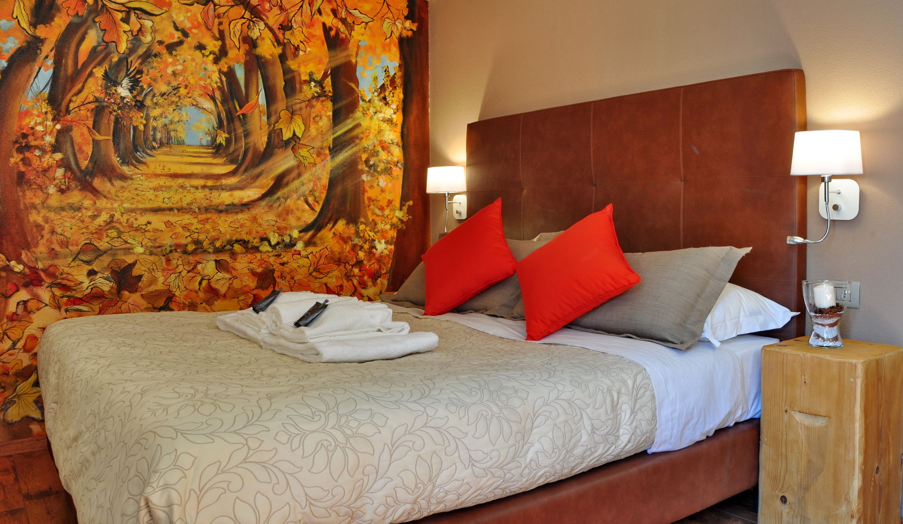 Une chambre d’hôtel avec un grand lit, une tête de lit, deux lampes de chevet, une table de chevet et une tapisserie au mur.