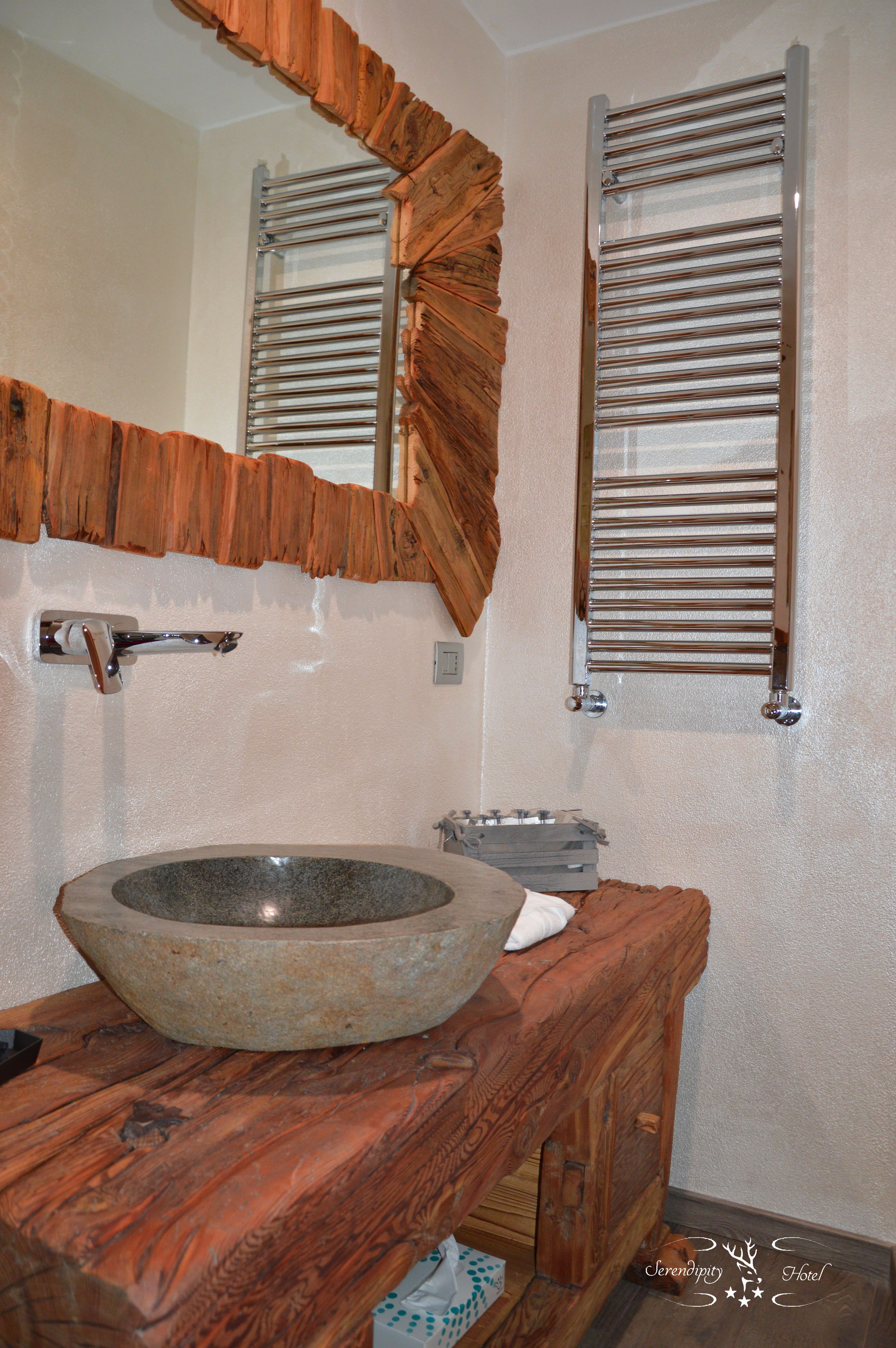 A bathroom with a stone sink, wooden vanity, and a mirror with wooden frame.