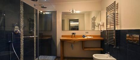 A modern bathroom with a glass shower enclosure, a wooden vanity, a bidet, and a toilet.