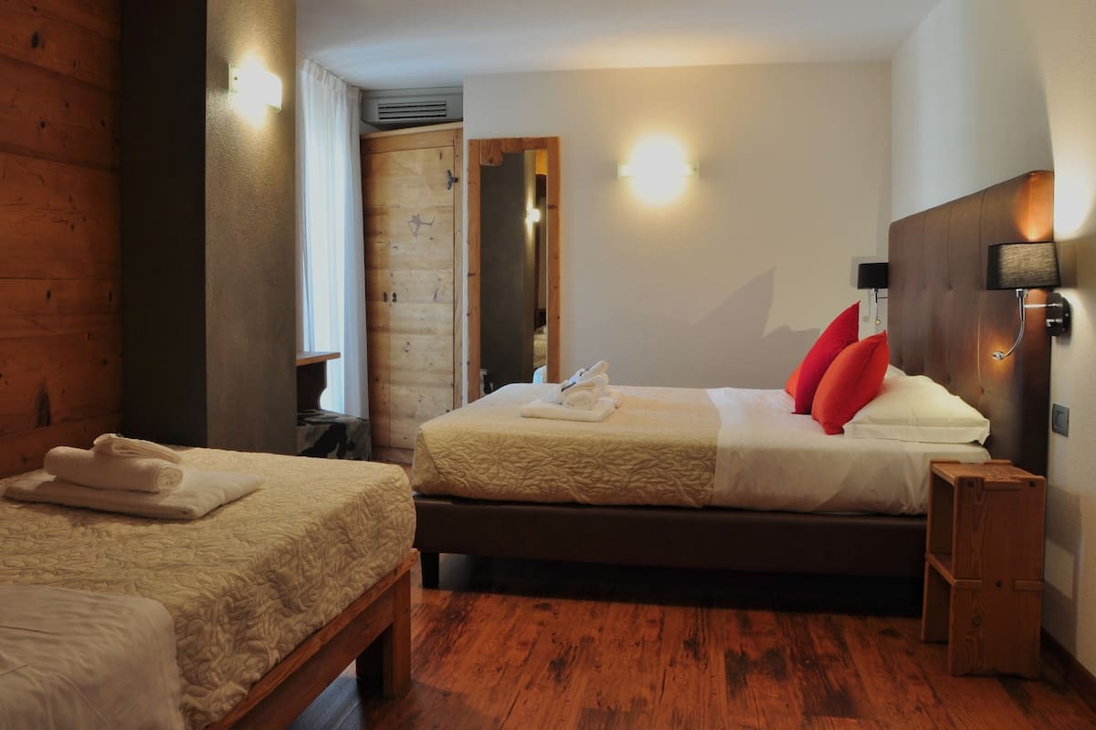 Une chambre d’hôtel avec deux lits, un plancher en bois, un miroir et une table de chevet avec une lampe.