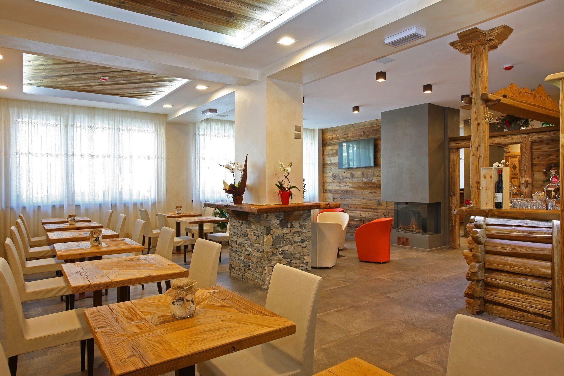 Un restaurant doté de nombreuses tables et chaises, d’une cheminée en pierre et d’une décoration en bois.