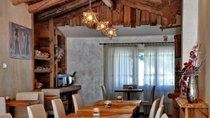 Un comedor rústico con mesas y sillas de madera, una zona de cocina con un tostador y una pared decorativa con una lámpara en forma de estrella.