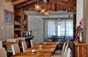 Un'area pranzo rustica con tavoli e sedie in legno, una zona cucina con un tostapane e una parete decorata con un lampadario a forma di stella.